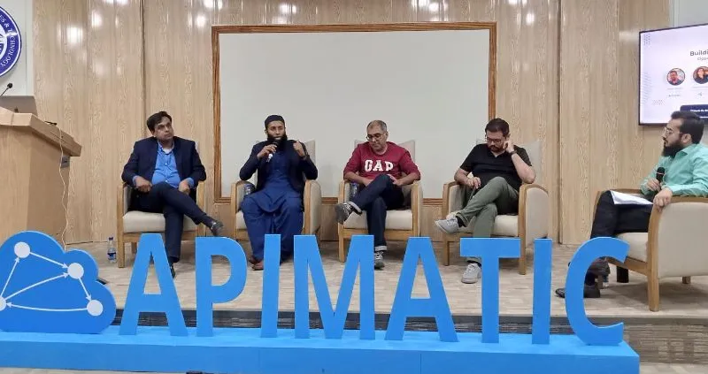 Sohaib Tariq moderating a five-person panel on stage in front of a large APIMatic sign in Islamabad