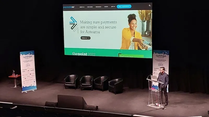 Sohaib Tariq presenting on stage at apidays London beside a large screen, with apidays London banners on either side